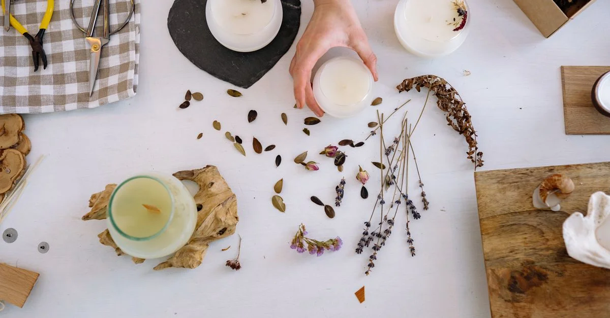Mise en place artistique pour la fabrication de bougies avec des fleurs séchées et des outils de bricolage.