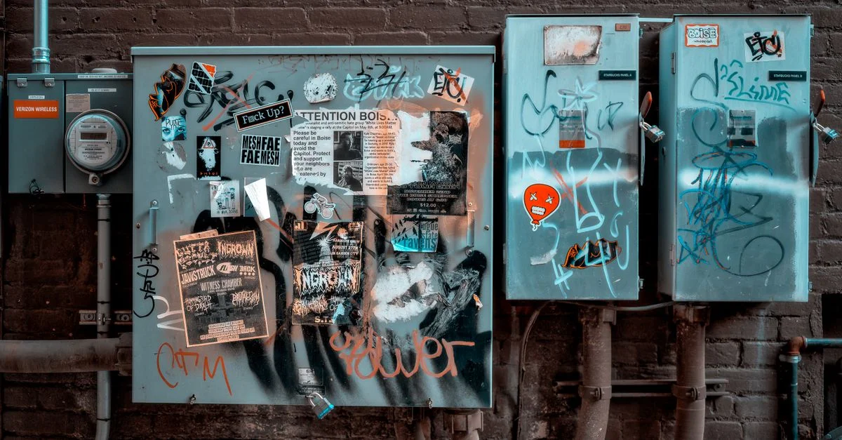 Art de rue urbain sur des caisses électriques mettant en avant des graffitis vibrants et un vandalisme ciblé.